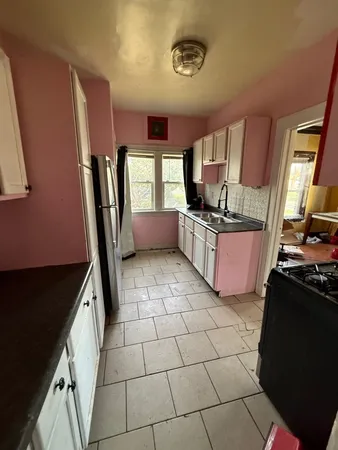 a kitchen with granite countertop a stove a sink and a refrigerator