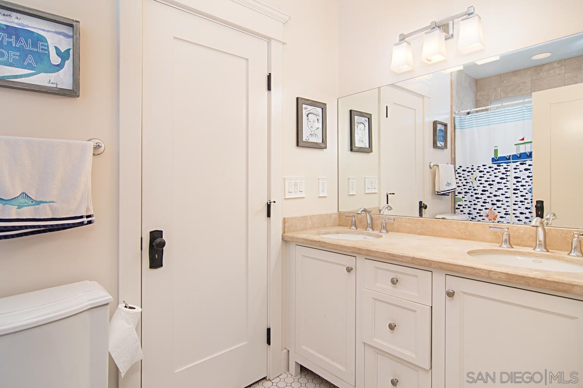 918 D Avenue Coronado, CA 92118 - Photo 27 of 41 a bathroom with a granite countertop sink a toilet and a mirror