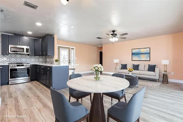 a kitchen with stainless steel appliances kitchen island granite countertop a kitchen island hardwood floor sink stove dining table and chairs