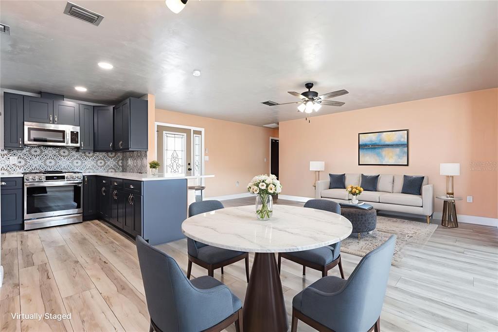 5108 Commonwealth Road Palmetto, FL 34221 - Photo 6 of 31 a kitchen with stainless steel appliances kitchen island granite countertop a kitchen island hardwood floor sink stove dining table and chairs