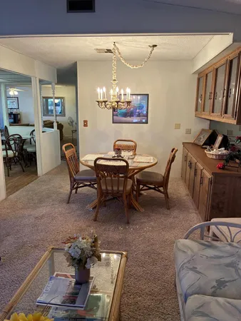 a view of a dining room with furniture a chandelier and kitchen view