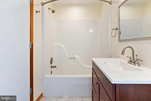 a view of a hallway with wooden floor and a bathroom