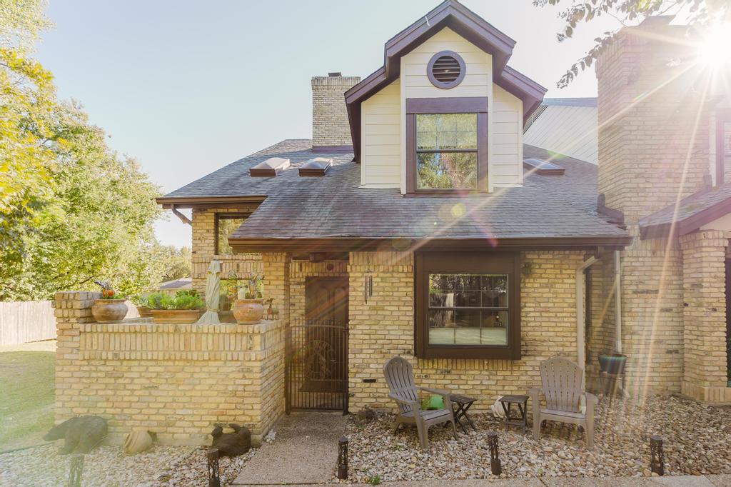 10819 Crown Colony Drive, Unit 40 Austin, TX 78747 - Photo 2 of 38 View of front of house featuring brick siding, a shingled roof, and a chimney