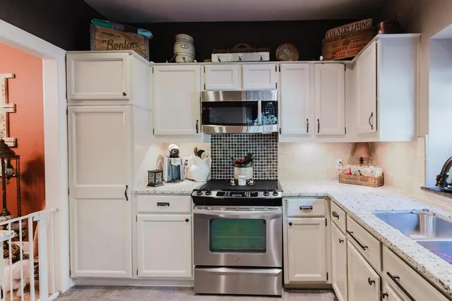 a kitchen with white cabinets and appliances