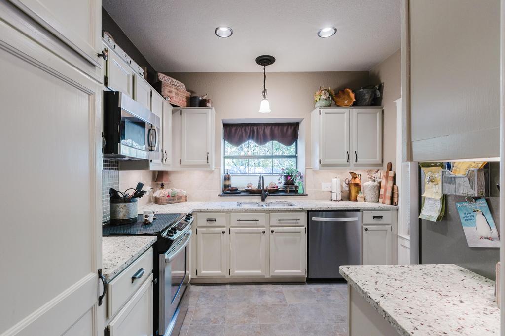 10819 Crown Colony Drive, Unit 40 Austin, TX 78747 - Photo 8 of 38 Kitchen featuring appliances with stainless steel finishes, pendant lighting, white cabinetry, light stone countertops, and backsplash