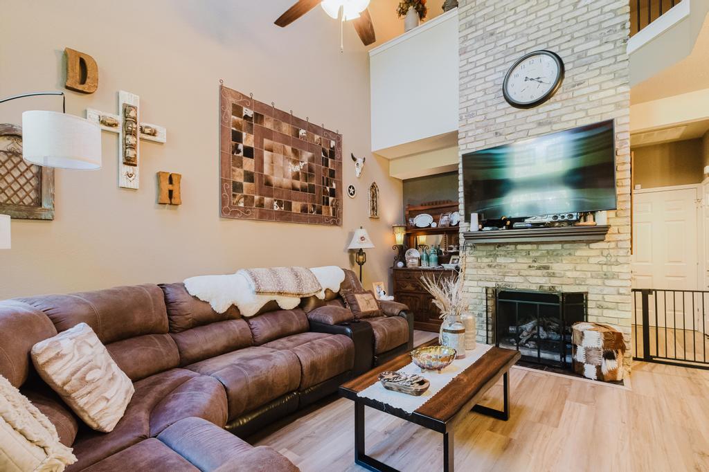 10819 Crown Colony Drive, Unit 40 Austin, TX 78747 - Photo 10 of 38 Living area featuring a high ceiling, a fireplace, ceiling fan, and wood finished floors