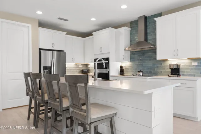a kitchen with stainless steel appliances kitchen island granite countertop a table chairs microwave and sink