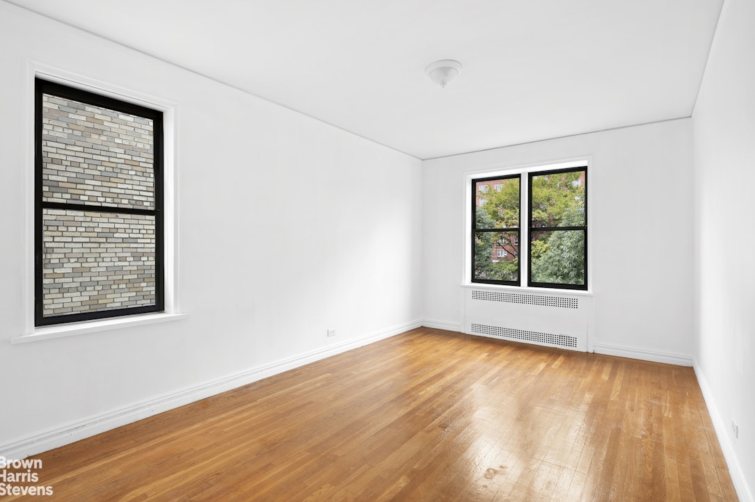 55 East 190th Street, Unit 41 Bronx, NY 10468 - Photo 4 of 8 an empty room with wooden floor and windows