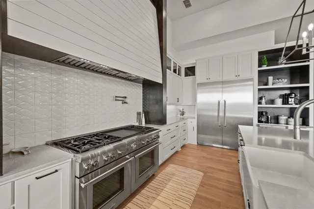 a kitchen with stainless steel appliances granite countertop a lot of cabinets a stove and a refrigerator