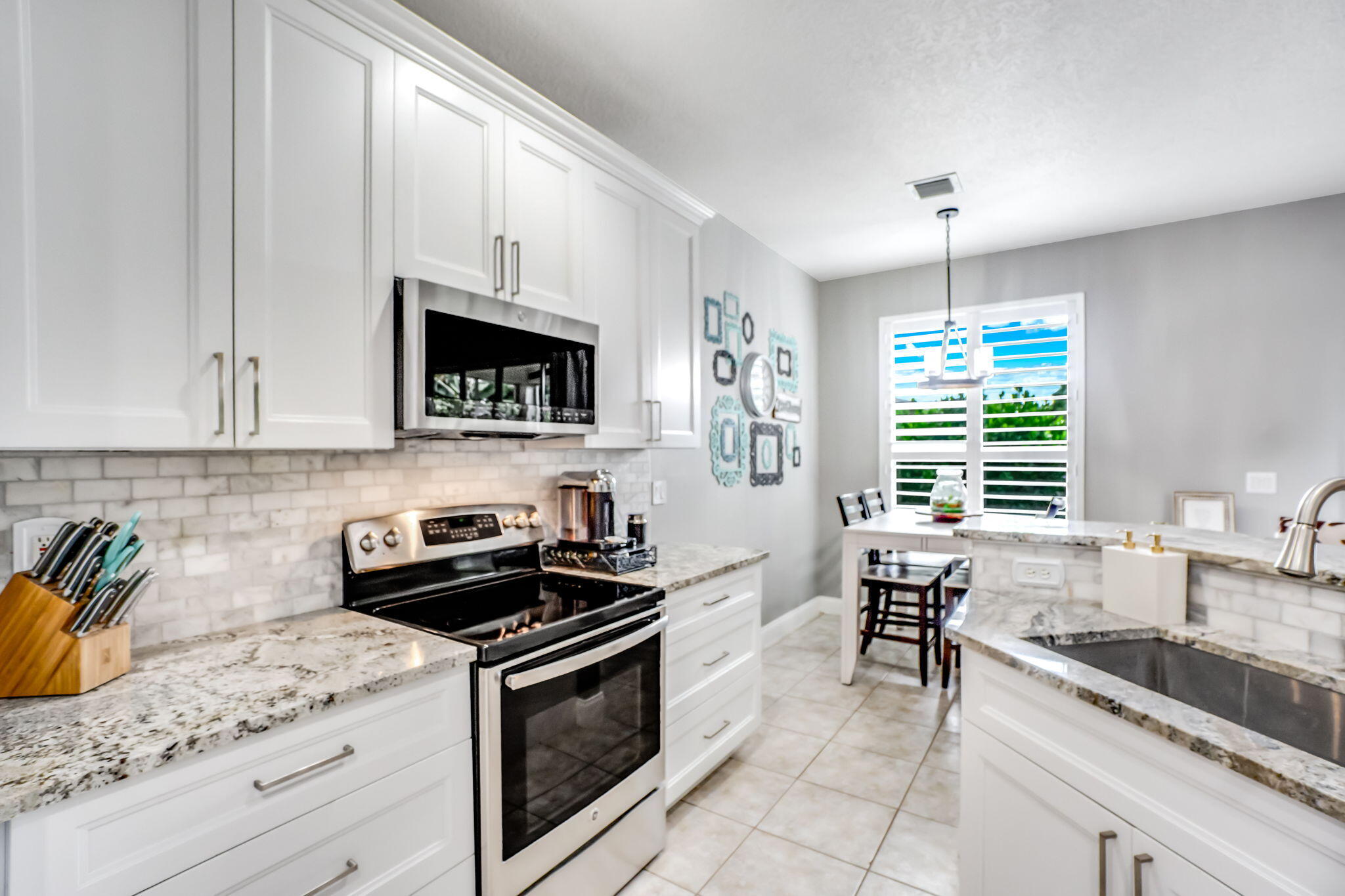 9760 Vineyard Court Boca Raton, FL 33428 - Photo 24 of 75 a kitchen with granite countertop a sink a stove and cabinets