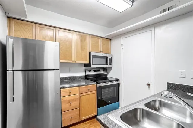 a kitchen with stainless steel appliances granite countertop a refrigerator sink and microwave