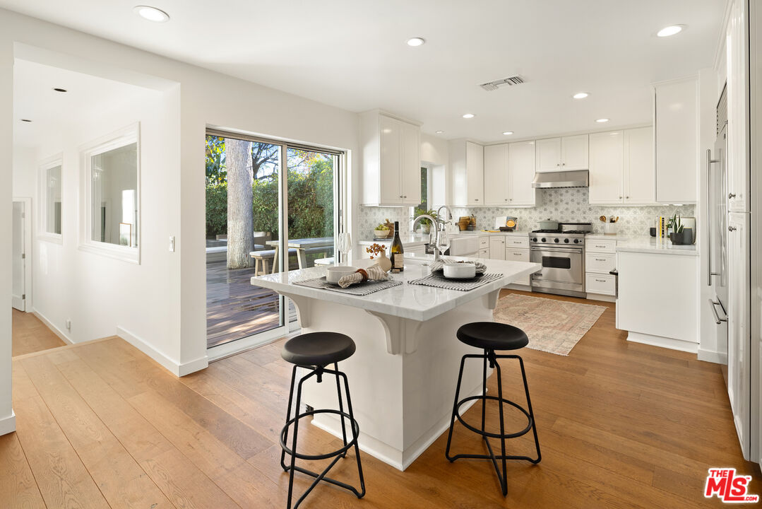 1314 Preston Way Venice, CA 90291 - Photo 19 of 37 a kitchen with stainless steel appliances kitchen island granite countertop a stove a refrigerator a sink a dining table and chairs with wooden floor