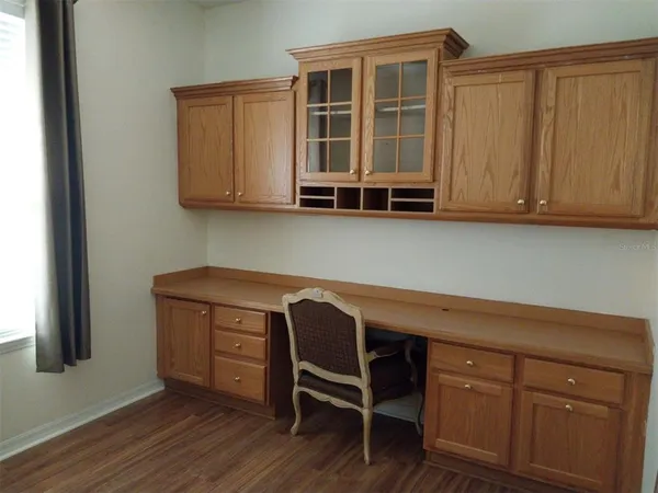 a bedroom with wooden floor and two windows