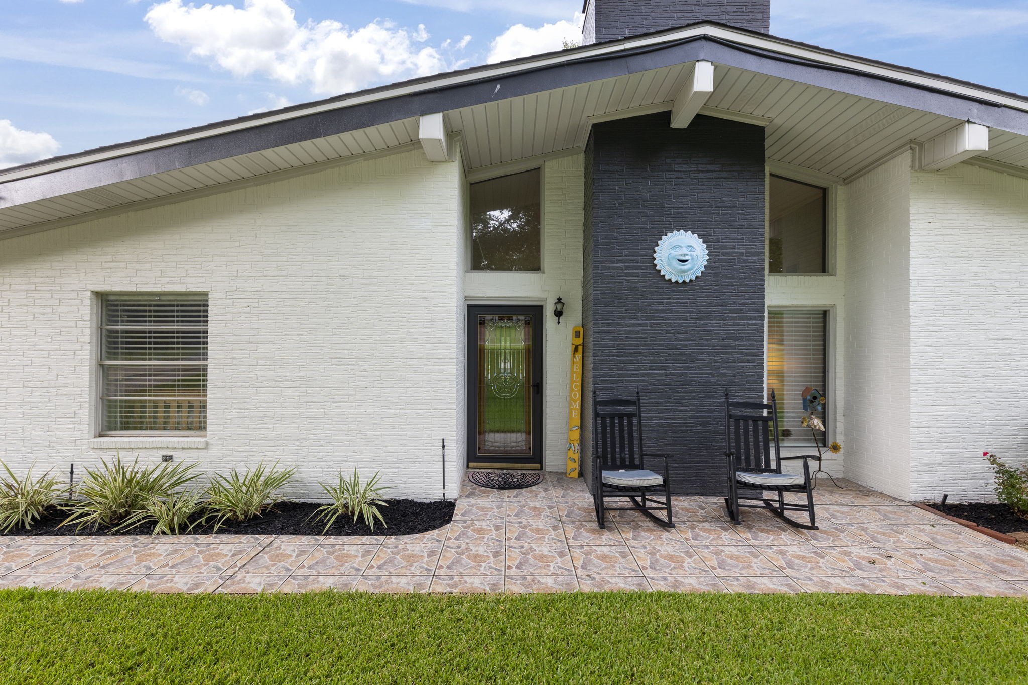 245 Lakeland Road Huntsville, TX 77320 - Photo 4 of 49 The front entrance of this home, featuring a modern white brick façade complemented by a sophisticated black brick fireplace, creating a welcoming and stylish entryway.