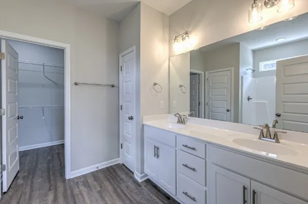 a spacious bathroom with a double vanity sink a large mirror a and shower