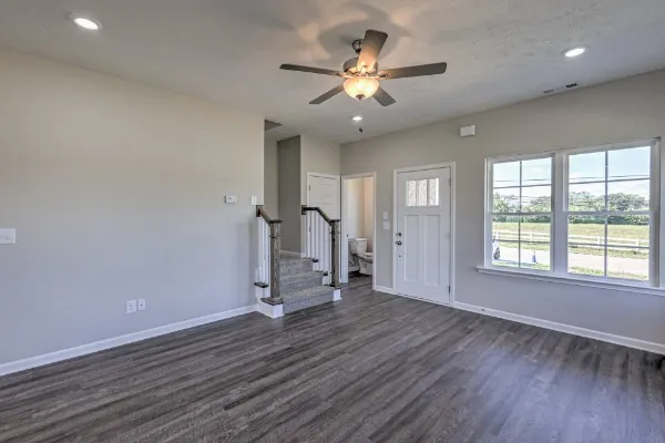 a view of an empty room with a window and wooden floor