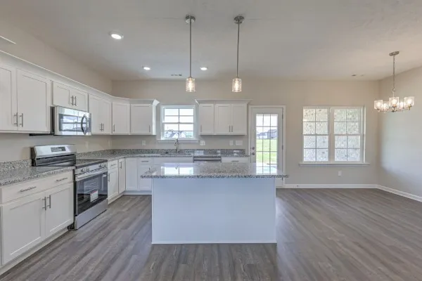 a large kitchen with stainless steel appliances granite countertop a stove a sink dishwasher a refrigerator white cabinets and wooden floor next to a window