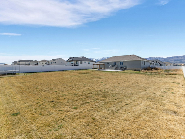 573 South Maxwell Drive Grantsville, UT 84029 - Photo 22 of 25 Fenced backyard featuring a gazebo, a patio area, a mountain view, a residential view, and a trampoline