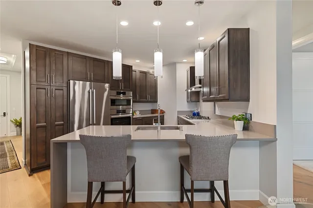 a kitchen with stainless steel appliances kitchen island granite countertop a refrigerator a stove a sink dishwasher with a dining table and chairs
