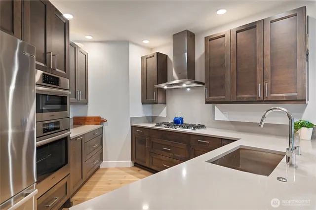 a kitchen with stainless steel appliances a sink a stove and a refrigerator with wooden cabinets