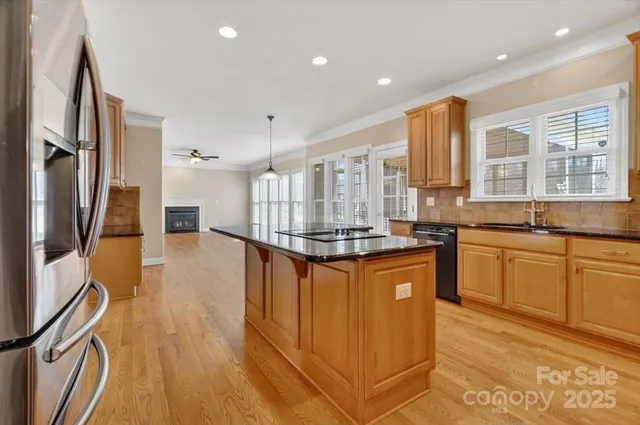 a kitchen with stainless steel appliances granite countertop a refrigerator a sink dishwasher a stove and white countertops with wooden floor