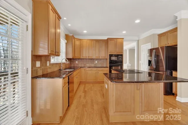 a kitchen with stainless steel appliances granite countertop a refrigerator a stove and a sink