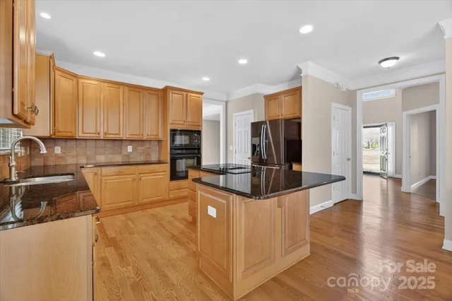 a large kitchen with stainless steel appliances a large counter top a stove and a refrigerator