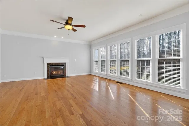 a view of an empty room with a window and wooden floor