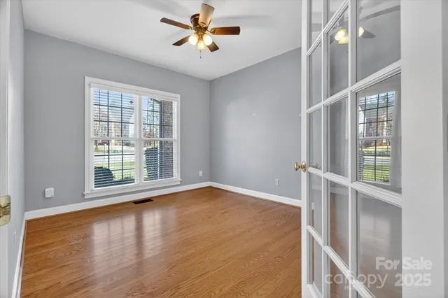 a view of an empty room with a window and wooden floor