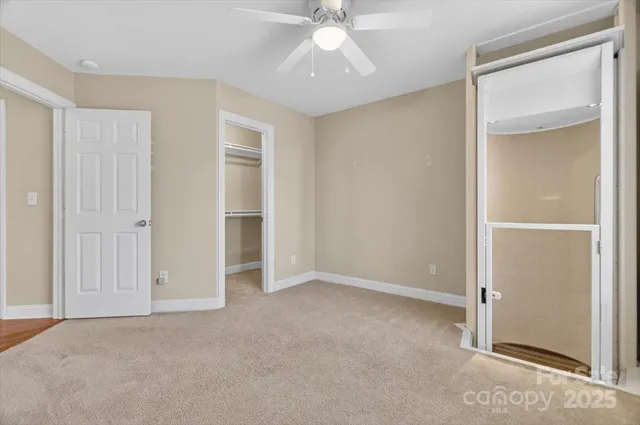 a view of an empty room with chandelier fan