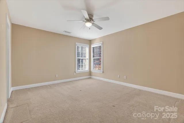 a view of an empty room with a chandelier fan