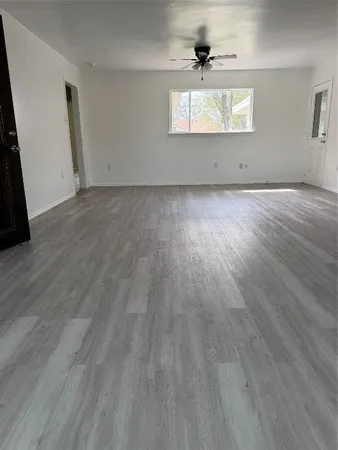 an empty room with wooden floor chandelier fan and windows
