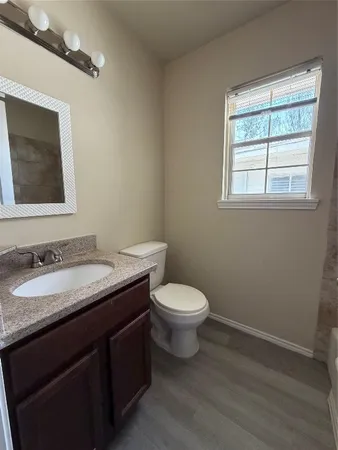 a bathroom with a granite countertop toilet sink and mirror