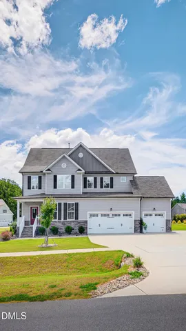 a front view of a house with a big yard and large trees
