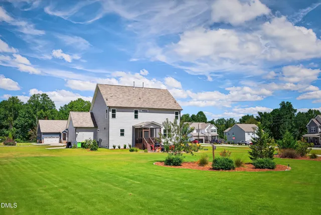 a view of a house with a big yard potted plants and a large tree