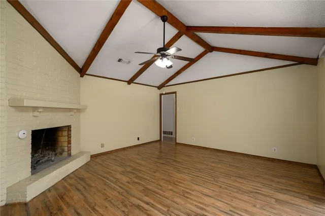 a view of an empty room with wooden floor and a fireplace