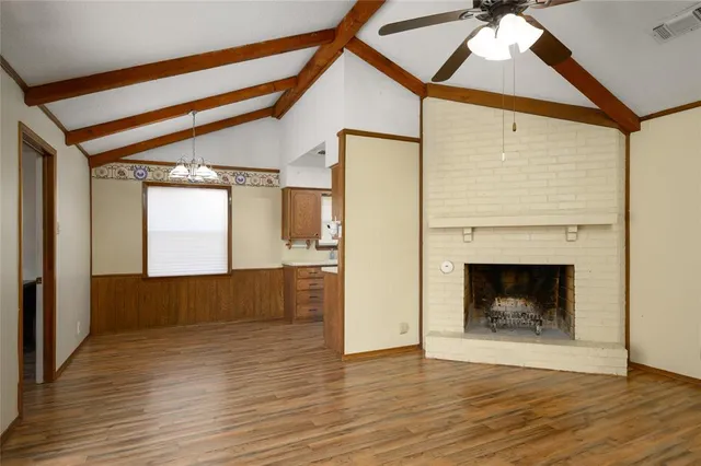 a view of an empty room wooden floor and a fireplace