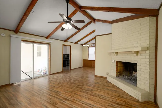 a view of an empty room with wooden floor fireplace and a window