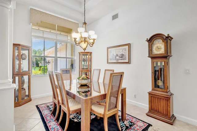 a dining room with wooden floor a chandelier fan a wooden table and chairs