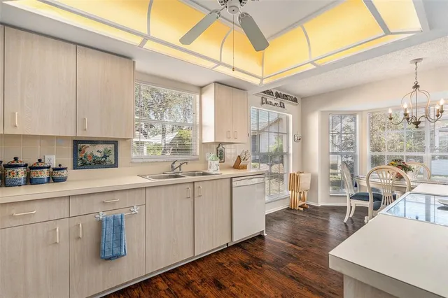 a kitchen with stainless steel appliances granite countertop a stove a sink and white cabinets with wooden floor