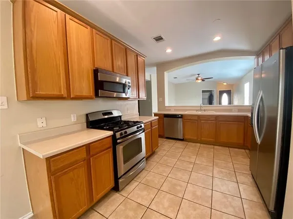a kitchen with stainless steel appliances granite countertop a stove a sink and a refrigerator