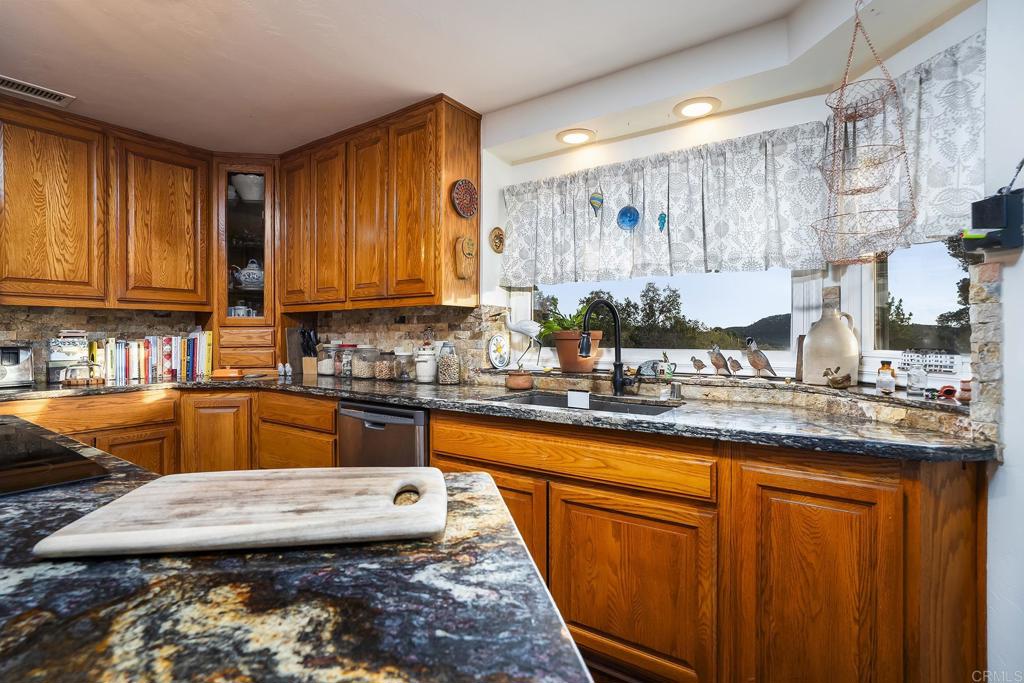 23002 Japatul Valley Road Alpine, CA 91901 - Photo 13 of 65 a kitchen with granite countertop wooden cabinets and a sink