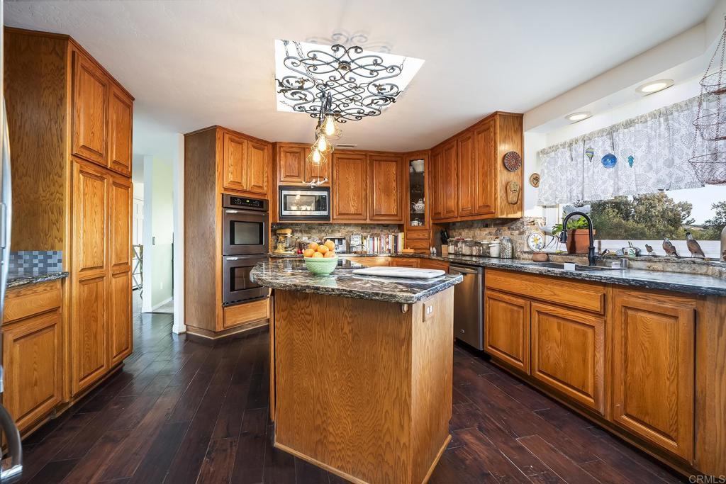 23002 Japatul Valley Road Alpine, CA 91901 - Photo 10 of 65 a kitchen with stainless steel appliances granite countertop wooden cabinets a sink a stove a dining table and chairs