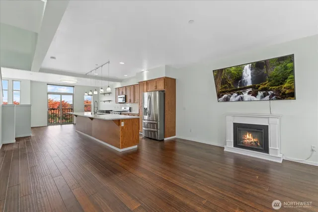a living room with stainless steel appliances furniture a fireplace a flat screen tv and view living room