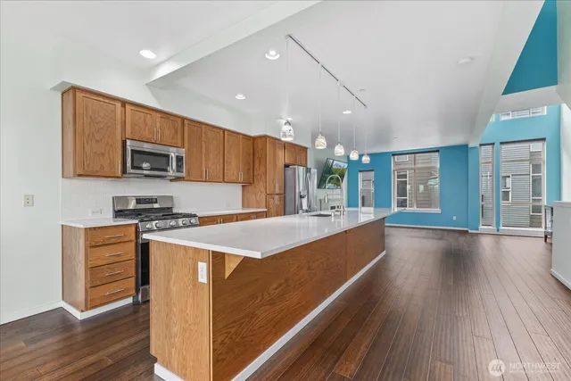 a large kitchen with stainless steel appliances granite countertop a stove a sink dishwasher and a microwave oven with wooden floor