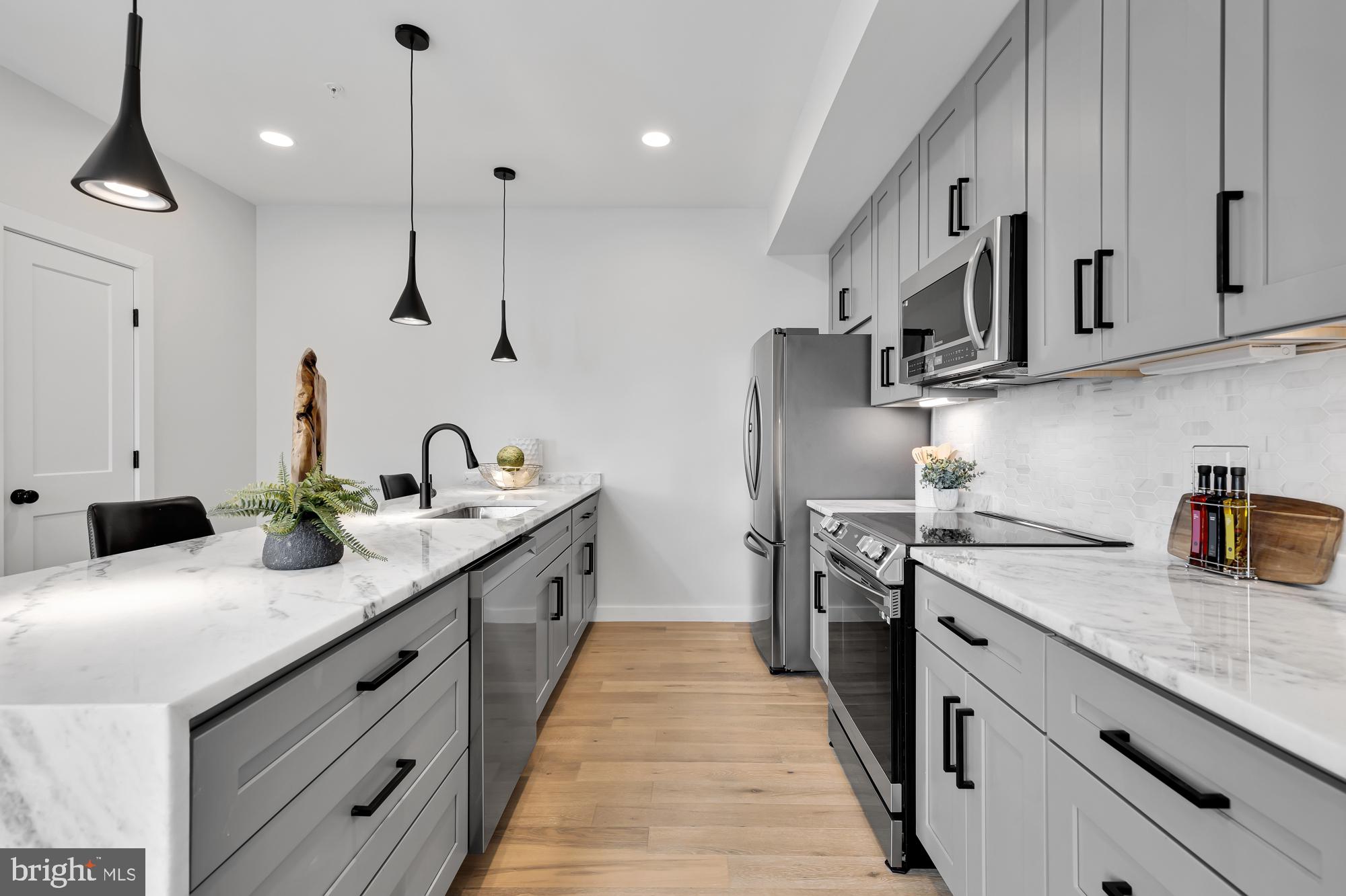 537 Park Road Northwest, Unit TH2 Washington, DC 20010 - Photo 18 of 60 a kitchen with stainless steel appliances kitchen island a white stove top oven a refrigerator white cabinets and wooden floor