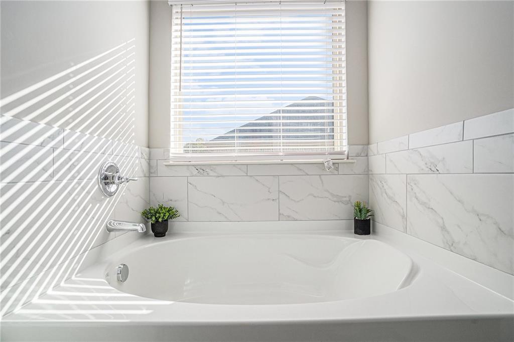 453 Sawmill Trace Hampton, GA 30228 - Photo 22 of 34 a white bath tub sitting in a bathroom next to a window