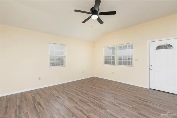 a view of empty room with wooden floor and fan