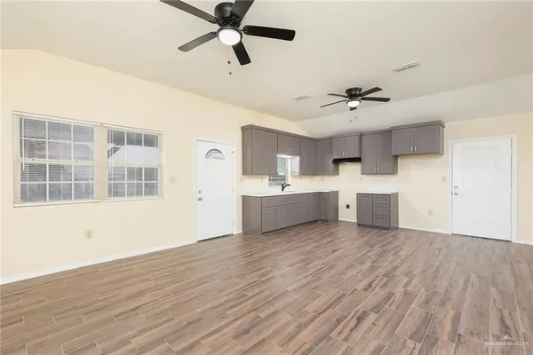 a view of a kitchen with a sink cabinet a ceiling fan and wooden floor