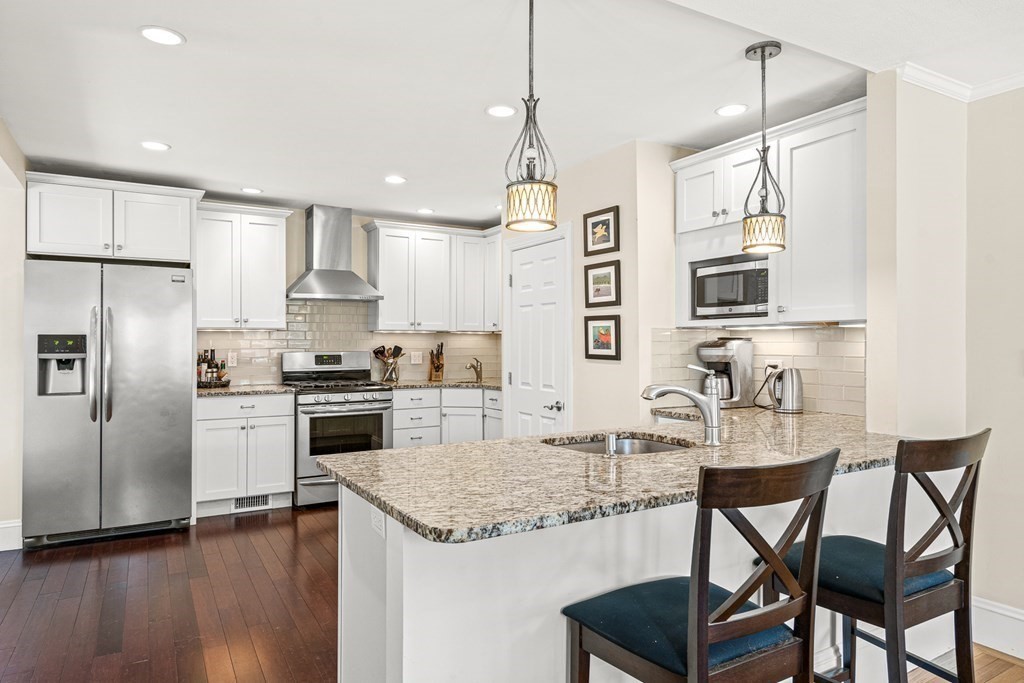 7 Perkins Avenue Reading, MA 01867 - Photo 10 of 42 a kitchen with granite countertop stainless steel appliances a refrigerator a stove a sink a dining table and chairs